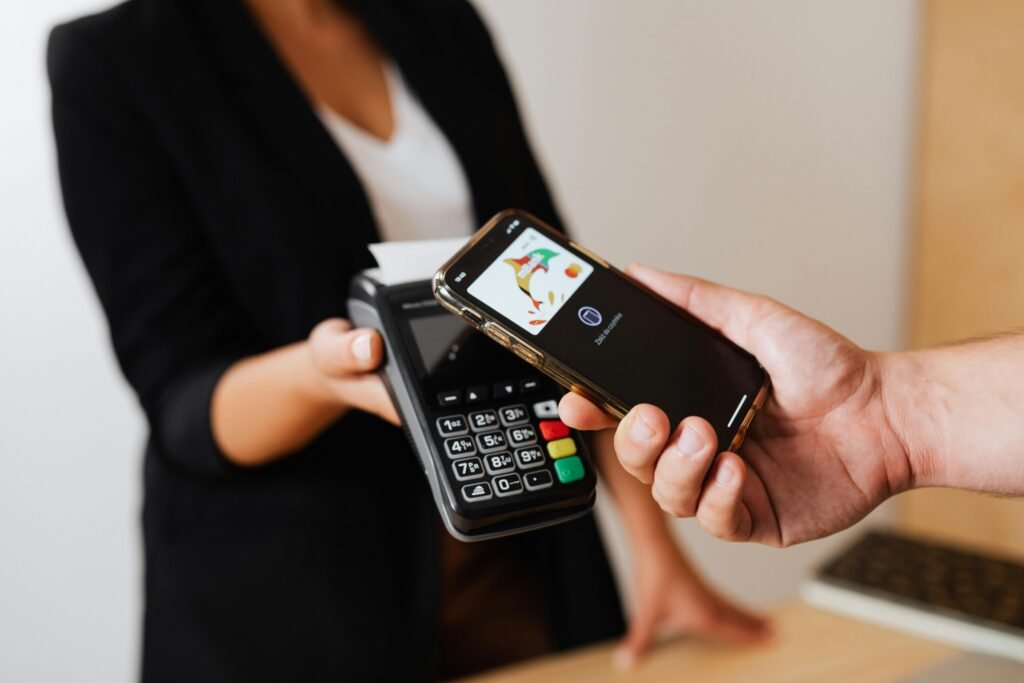 pexels-photo-5239806-5239806 A person using a smartphone for contactless payment at a retail store counter.